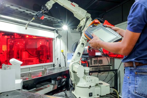 Engineer using wireless remote for control industrial robot